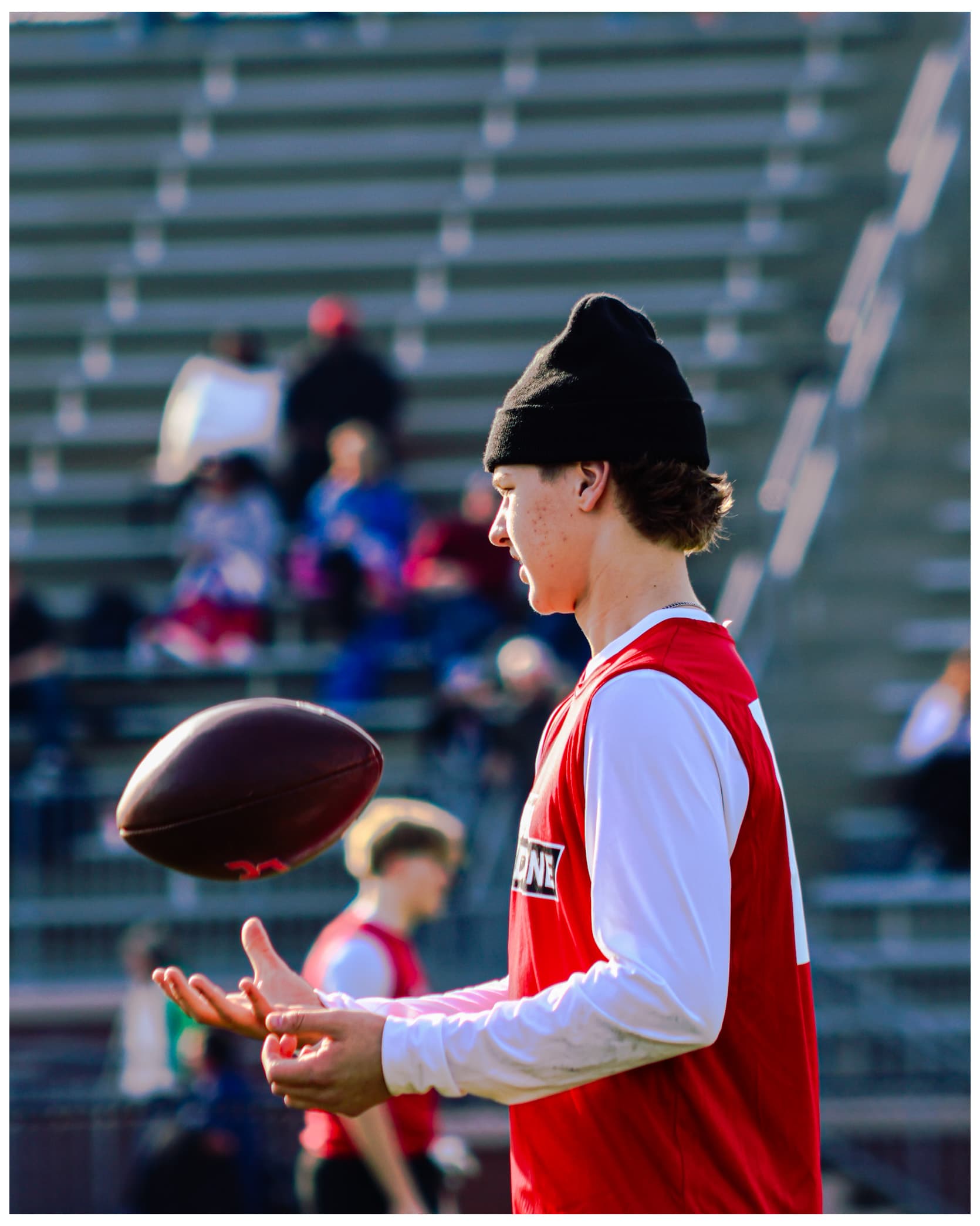 Player tossing football with black beanie in stadium