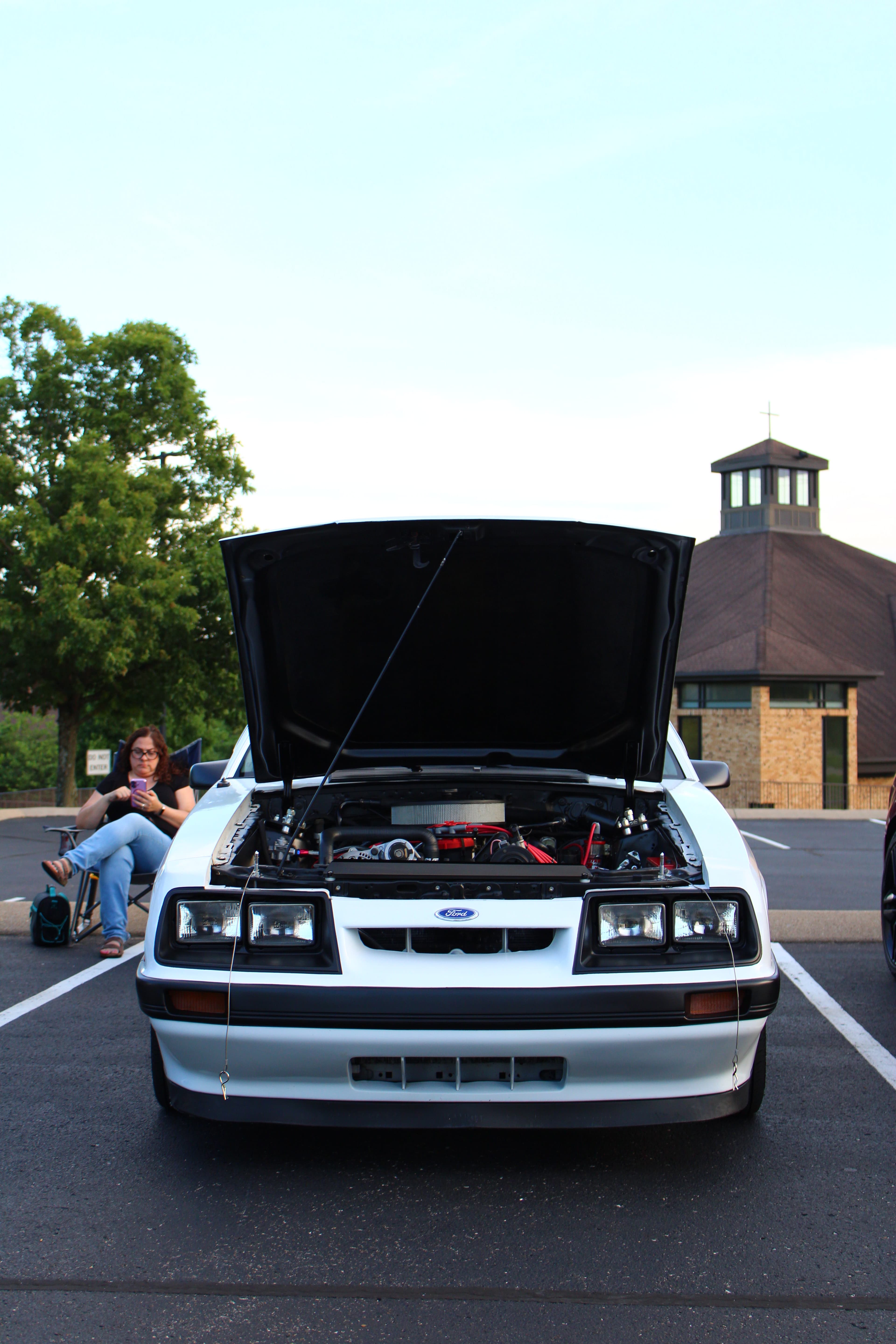 White Ford Mustang with hood open showing engine