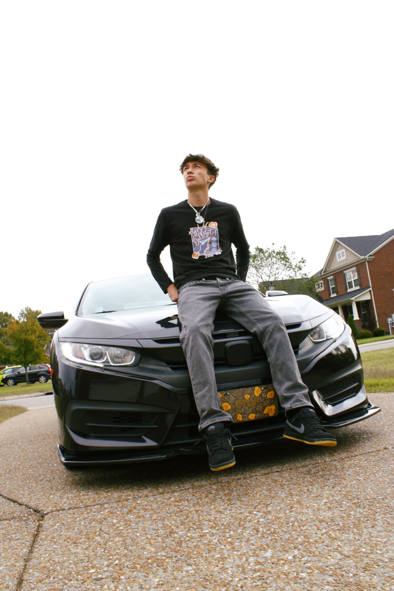Black Chevrolet Camaro with person sitting on hood