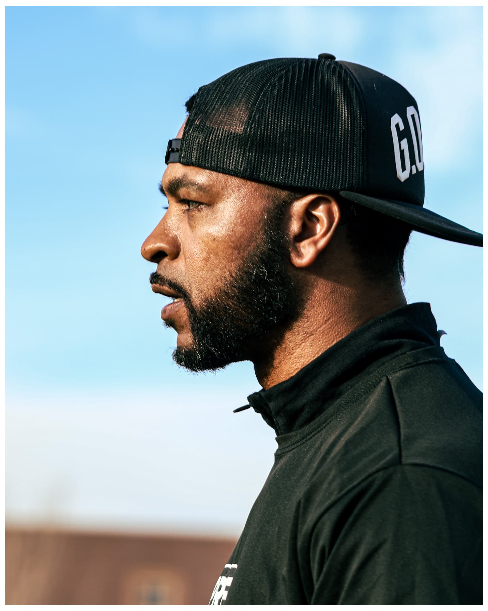 Coach profile portrait with G.O cap against blue sky